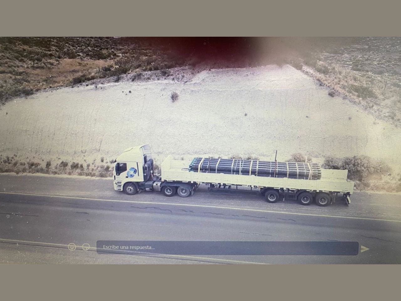 Batea de volteo lateral transportando caños en la ruta